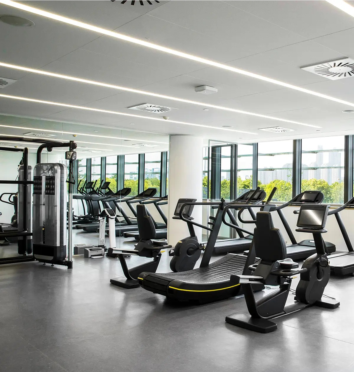 Modern gym with exercise equipment and windows.